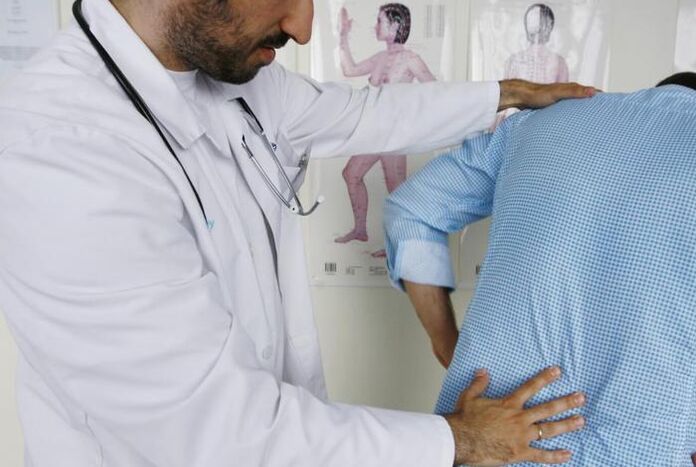A doctor examines a patient with back pain in the lumbar region